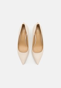 Beige nahkakorkokengät terävillä kärjillä ja sileällä pinnalla. Sisäpuolella pehmeä beige vuori. Ei näkyviä metalliosia tai koristeita.