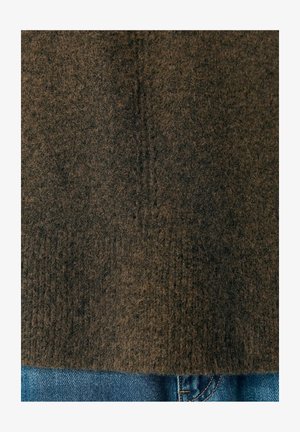 Pull en tissu brun avec une apparence douce et duveteuse, doté d'un ourlet droit. Associé à un jean en denim bleu, créant un look superposé.