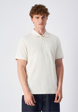 Crème polo met een klassieke kraag, drie knopen, korte mouwen en een subtiele logo-accent op de borst. Vette katoenstructuur.