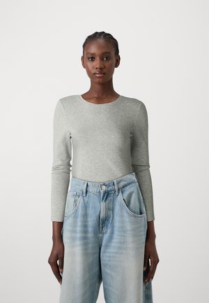 Gray long-sleeve shirt in cotton blend paired with light blue high-waisted jeans. Shirt features a round neckline and fitted silhouette.