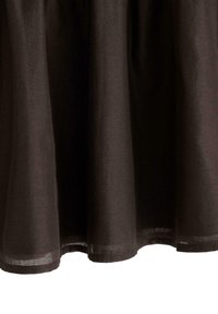 Sort linned nederdel med et flydende design, der har en kant med en subtil bølget kant og let, tekstureret stof.