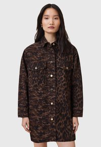 Vestito camicia in camouflage marrone e stampa leopardata, con bottoni frontali, due tasche sul petto e vestibilità comoda. Realizzato in tessuto resistente.