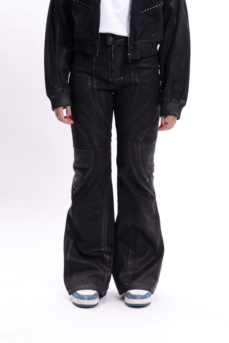 Μαύροι φαρδυί παντελόνια φτιαγμένα από υφασμάτινη με υφή, με καμπύλες ραφές και μπροστινές τσέπες, συνδυασμένα με μπλε και λευκά αθλητικά παπούτσια.