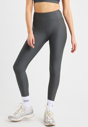 Hoge taille, geribbelde leggings in donkergrijs met een soepele textuur. Gepaard met zilveren sportschoenen en witte enkelsokken met logo.
