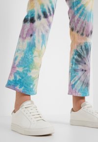 T-shirt met een rechte pasvorm in blauw, paars en crème, met een onafgebroken zoom. Gecombineerd met witte sneakers met een beige accent.