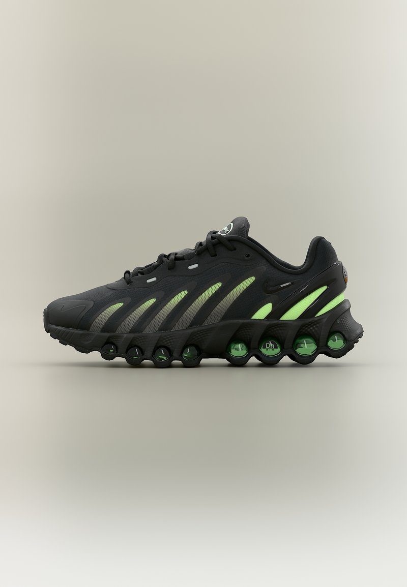 Μαύρο και νέον πράσινο αθλητικό παπούτσι με μοναδικά κυκλικά μαξιλαράκια αερόσολας στη σόλα, εμφανιζόμενο σε προφίλ σε απλό φόντο.