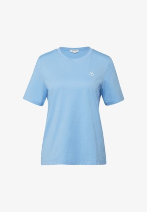 Jasnoniebieska koszulka z krótkim rękawem i okrągłym dekoltem, z małym białym serduszkiem i napisem „Adored” na lewej piersi, na jednolitym tle.