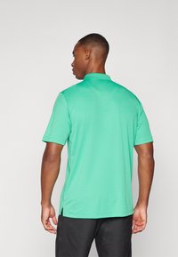 Πράσινο πόλο μπλουζάκι κοντό μανίκι με γιακά, διαθέτοντας απαλή υφή, πλαϊνές σχισμές και ένα απλό, μονόχρωμο σχέδιο.