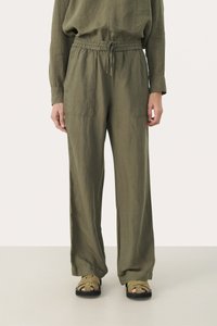 Olijfgroene linnen broek met een elastische tailleband, twee voorzakken en een losse pasvorm, gecombineerd met tan kleurige strappy sandalen.
