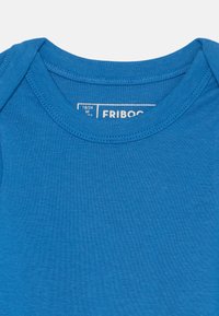 Zils kokvilnas T-krekls ar apaļu kakla izgriezumu, īsām piedurknēm un maigu, gludu tekstūru. Etiķete norāda "FRIBOO," izmērs 18/24 mēneši.