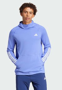 Hellblauer Sportpullover mit hohem Kragen, weißem Adidas-Logo und weißen gestreiften Akzenten an den Ärmeln. Glatter Stoff mit legerer Passform.