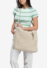 Borsa a tracolla in paglia intrecciata di colore avorio, con un motivo texturizzato, di grande dimensione e con una tracolla beige. Include un portachiavi come dettaglio aggiuntivo.