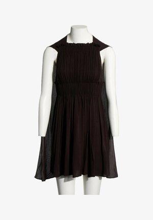 Robe noire sans manches avec corsage froncé et jupe fluide exposée sur un mannequin blanc sans tête sur fond blanc.