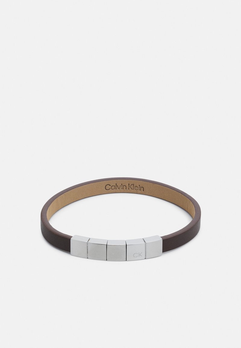 Bracelet en cuir marron avec cinq perles en métal argenté, dont une gravée "CK", et marquage "Calvin Klein" à l'intérieur.