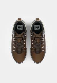 Zapatos de senderismo marrones con parte superior de cuero y malla, ojales de metal, cordones en contraste y una suela de goma negra texturizada.