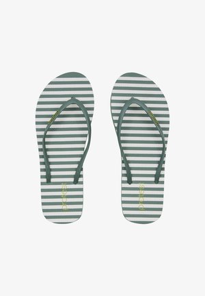 Slippers met donker groene banden en witte zolen met horizontale donker groene strepen en gele "protest"-bedrukking op elke zool.