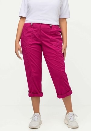 Fuksia cropped-housut etutaskuilla, käännettävillä hihoilla ja nappikiinnityksellä, yhdistettyinä valkoisiin tennareihin ja yksinkertaiseen valkoiseen t-paitaan.