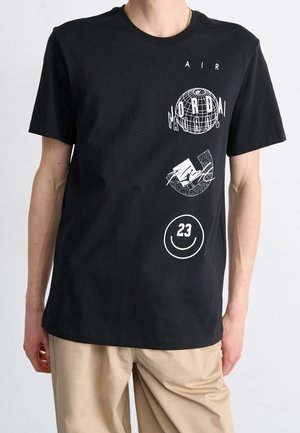 Schwarzes Baumwoll-T-Shirt mit weißen Grafiken, darunter eine Erdkugel und ein Smiley-Gesicht, mit kurzen Ärmeln und Rundhalsausschnitt.