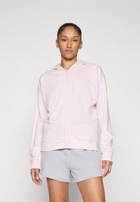 Roosa tõmblukuga kapuutsiga sviiter, mis on valmistatud pehmest materjalist, ning sellel on valge logo rinna peal. Koos heledate hallide lühikestega.