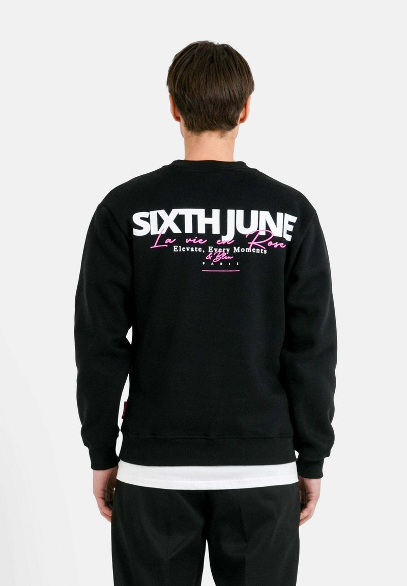 Zwarte sweatshirt met witte en roze tekst op de achterkant, met "SIXTH JUNE" en aanvullende merkdetails. Glad stof met ribbel manchetten.