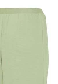Pantaloni verde chiaro con cintura elastica, dalla finitura testurizzata e con tasche laterali. Presentano un taglio loose e rilassato, con design plissettato.