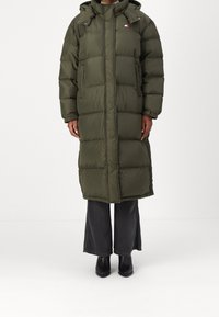 Puff jacka i olivgrön färg med full dragkedja, huva och logodetaljer. Har en quiltad design och rymlig passform, som når till mitten av vaden.