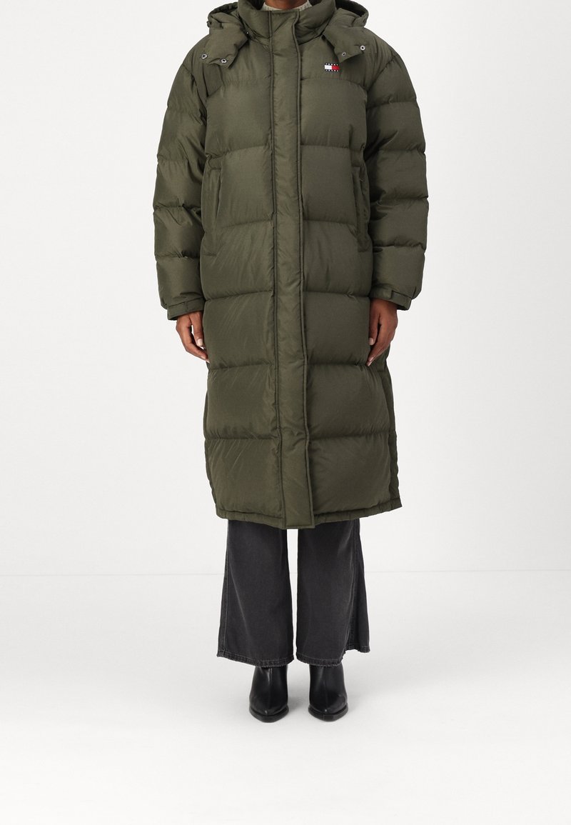 Puff jacka i olivgrön färg med full dragkedja, huva och logodetaljer. Har en quiltad design och rymlig passform, som når till mitten av vaden.