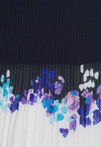 Tissu plissé en bleu marine en haut qui se fond en une base blanche ornée de motifs floraux aquarelles en violet et bleu.