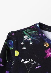 Svart tyg med färgglatt blommönster som inkluderar rosor, prästkragar och andra blommor. Rund halsringning och slät textur, designad för komfort.