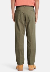 Olive green cotton trousers with a relaxed fit, featuring two back pockets, and a visible brand label at the waistband.
