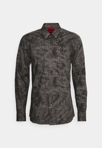 Chemise boutonnée à manches longues de couleur gris foncé avec une surface texturée présentant un motif noir moucheté. Elle possède un col pointu et des poignets boutonnés.