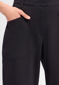 Zwarte broek met een gladde textuur. Heeft een zijzak met een rechthoekige vorm en een gestikte zoom. Ontworpen voor een slim fit uitstraling.