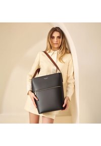 Sort læder tote bag med en lynlåslomme, udstyret med en brun skulderrem og glat overflade. Struktureret design med en minimalistisk æstetik.
