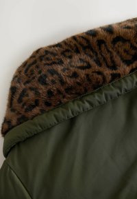 Vihreä pehmustettu takki, jossa on leopardikuosiset tekoturkistennä. Kangas on sileä ja kiiltävä, kun taas kaulus on pehmeä ja teksturoitu pinta.