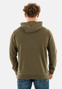 Haut à capuche vert olive avec cordon de serrage, poignets et ourlet côtelés. Matériau en mélange de coton ; détails de couture minimalistes au dos.