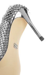 Scarpa con tacco alto in argento, con una tomaia testurizzata decorata da borchie, punta brillante in vernice e sottile tacco a stiletto.