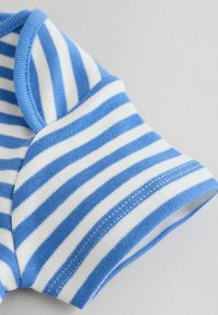 Plavi i bijeli vodoravni prugasti kratki rukav na mekoj pamučnoj tkanini, prikazujući prošivenu ivicu i šav na rukavu na svijetloj pozadini.