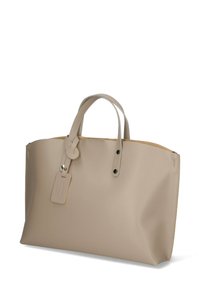 Borsa tote in pelle beige con superficie liscia, manici corti e un'etichetta per bagagli. Presenta due rivetti neri ai lati.