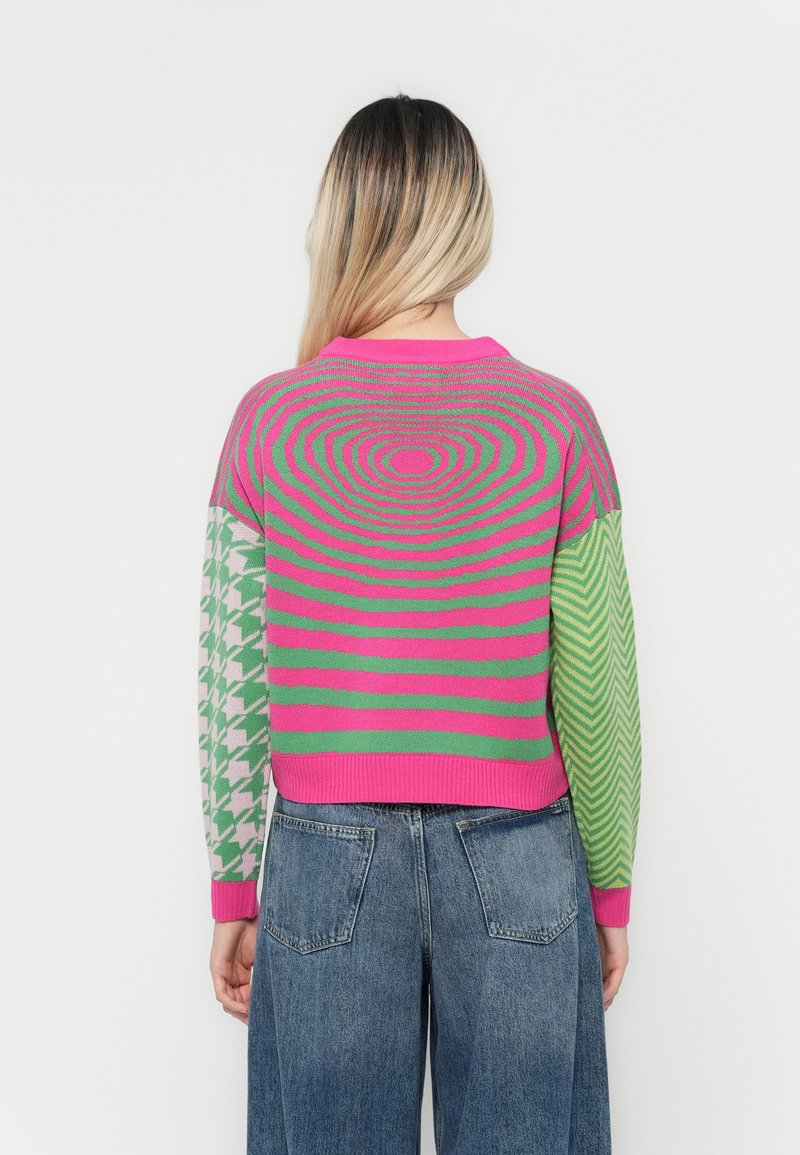 Kolorowy sweter robiony na drutach z spiralnym wzorem w różowym i zielonym na plecach, z wzorami w pied de poule i zygzakami na rękawach.