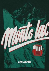 Horská krajina s červenou lanovkou, veľkým bielym textom "Monte lac" a menším textom "Les Alpes" na tmavozelenom pozadí.