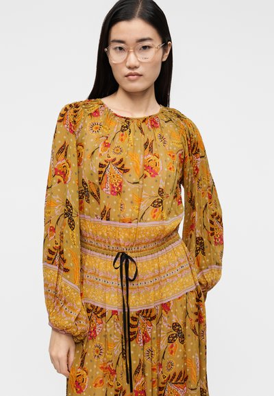 Φλοράλ φόρεμα με μακριά μανίκια, κίτρινο βάθος και πολυχρωματικά μοτίβα. Διαθέτει σούρα στο ντεκολτέ και μέση με κορδόνι και αντίθετες λεπτομέρειες.