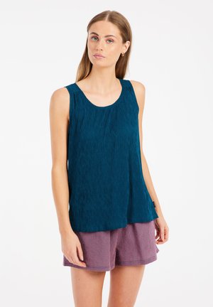 Teal mouwloos topje met een gestructureerd ontwerp, ronde halslijn en een losse pasvorm, gecombineerd met roze geruite shorts.