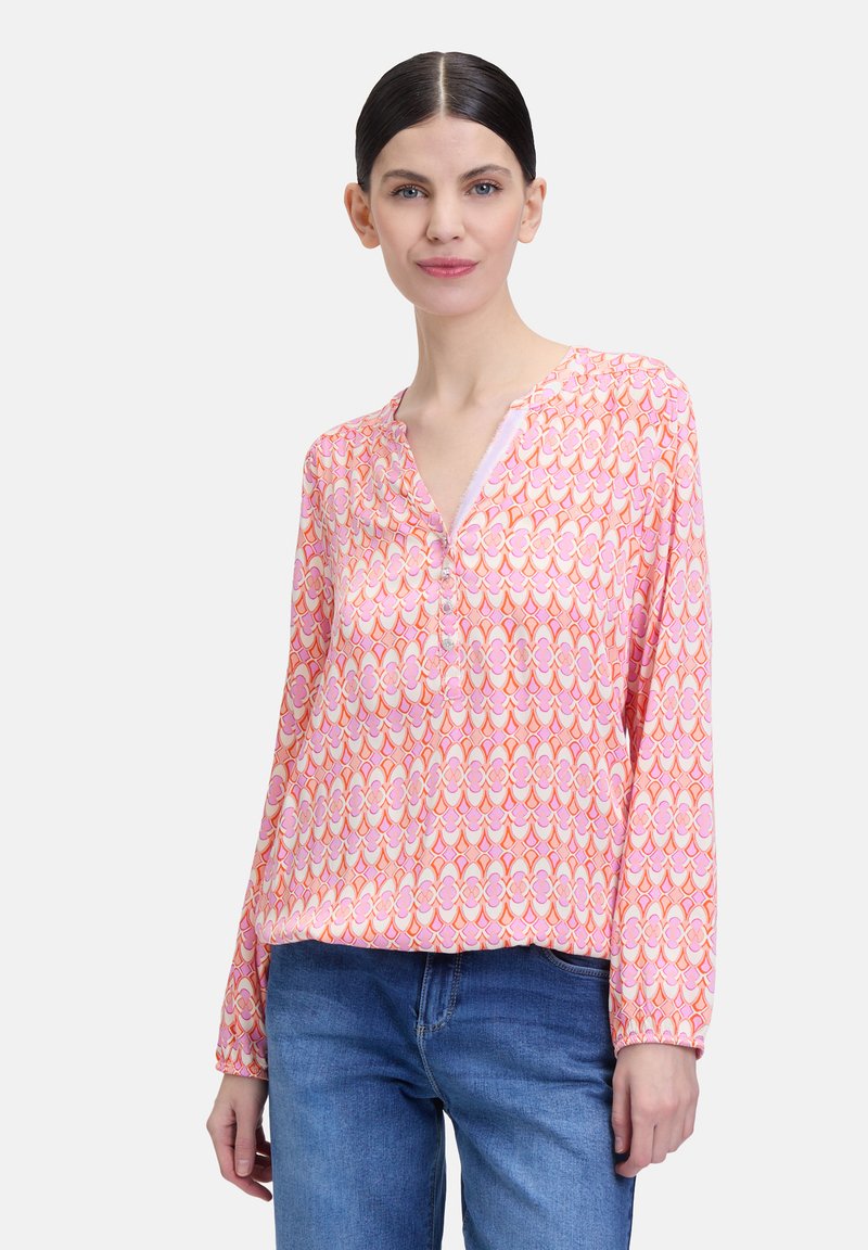 Blouse à manches longues en tissu rose avec un motif géométrique, présentant un col en V, de délicats boutons et des poignets élastiques.
