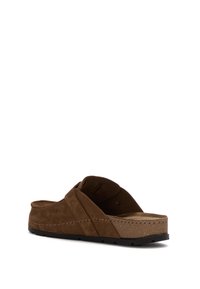 Sandalo in suede marrone, a slip-on, con suola in sughero imbottita e cinturino regolabile, inclinato per mostrare i dettagli laterali e posteriori su sfondo bianco.