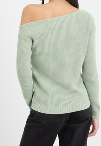 Vaaleanvihreä, ribbineulottu neulepaita olkapäät paljastavalla designilla ja pitkillä hihoilla, jossa on istuva helma ja rento siluetti.