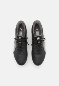 Zapatillas deportivas negras con un acabado de cuero suave, acentos laterales de malla gris, cordones redondos y una plantilla con un patrón que presenta el logotipo de Puma.