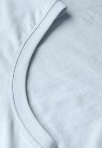 Světle modré bavlněné tričko s kulatým výstřihem, měkkou texturou a hladkým povrchem se jemným žebrovaným lemováním kolem límce.