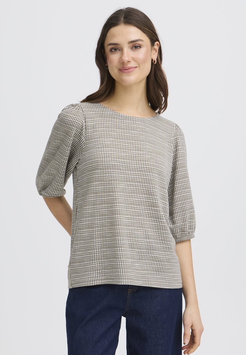 Blouse à carreaux beige avec manches courtes bouffantes, encolure ronde et coupe décontractée, fabriquée dans un tissu léger et texturé.