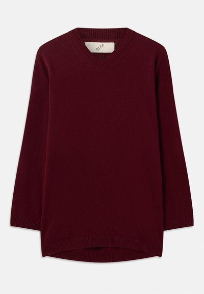 Bordowy sweter z dekoltem w serek, wykonany z miękkiego materiału, ma długie rękawy oraz ściągacz na dekolcie i dolnym krańcu, z zaokrąglonym dołem.
