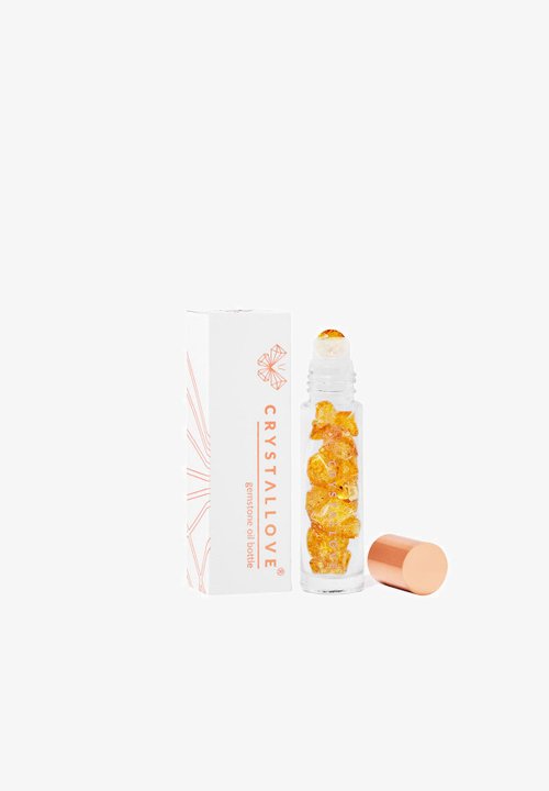 Bottiglia a rullo in vetro trasparente riempita di cristalli dorati, con un tappo metallico rosé, accanto a una scatola bianca con accenti arancioni e logo.
